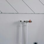 White wall with minimalist plumbing pipes and diagonal lines